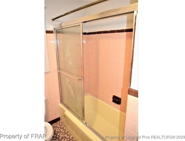 bathroom featuring shower / bath combination with glass door and toilet