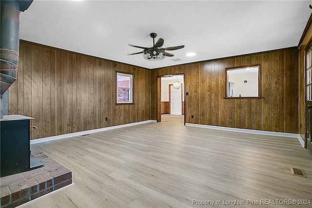 unfurnished living room featuring light hardwood / wood-style flooring, ceiling fan, and wooden walls