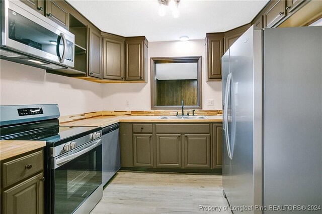 kitchen with wood counters, light hardwood / wood-style floors, sink, and stainless steel appliances