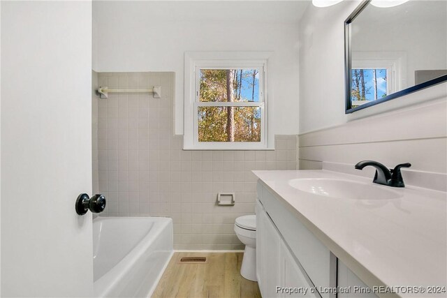 full bathroom featuring vanity, separate shower and tub, toilet, tile walls, and wood-type flooring