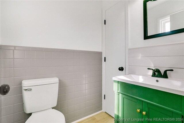 bathroom featuring wood-type flooring, vanity, and tile walls