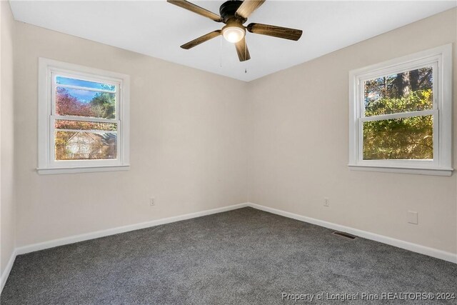 spare room with ceiling fan and dark carpet