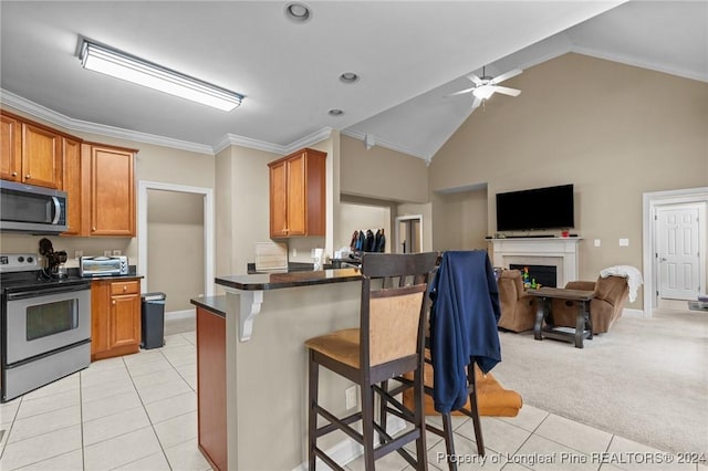 kitchen with kitchen peninsula, a breakfast bar, stainless steel appliances, light tile patterned floors, and high vaulted ceiling