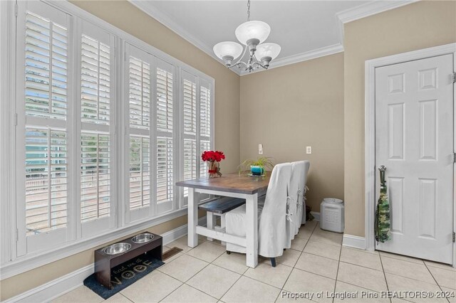 dining space with light tile patterned floors, ornamental molding, and a chandelier