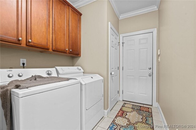 clothes washing area with washer and dryer, light tile patterned floors, crown molding, and cabinets