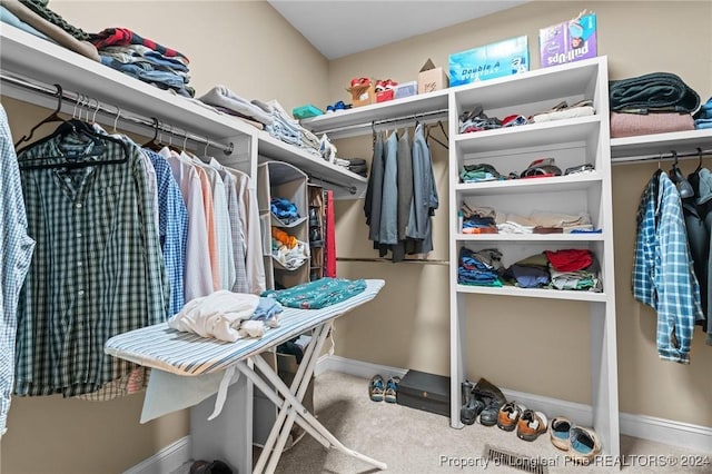 walk in closet with light carpet