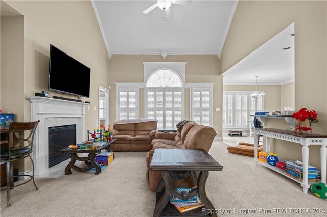 living room featuring carpet flooring, a premium fireplace, ceiling fan with notable chandelier, and ornamental molding