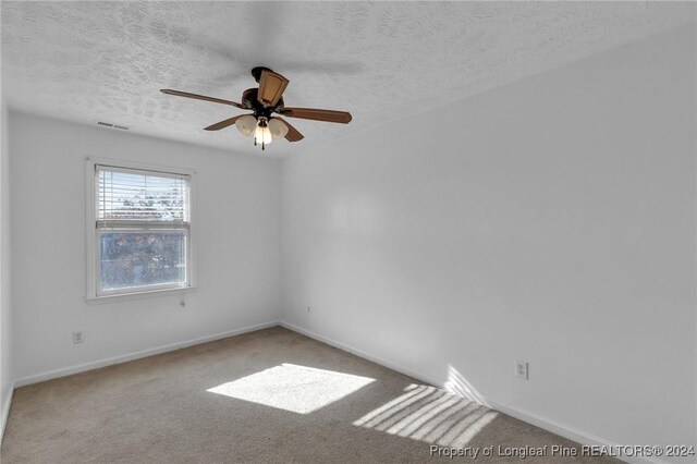 empty room featuring carpet flooring, a textured ceiling, and ceiling fan