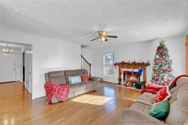 living room featuring ceiling fan with notable chandelier, hardwood / wood-style floors, a textured ceiling, and crown molding