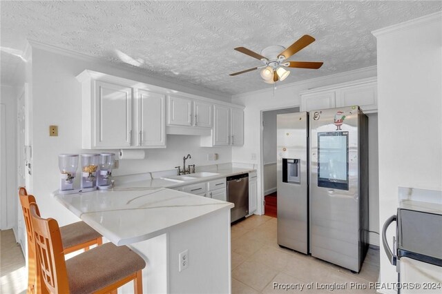 kitchen featuring a kitchen bar, appliances with stainless steel finishes, and white cabinetry