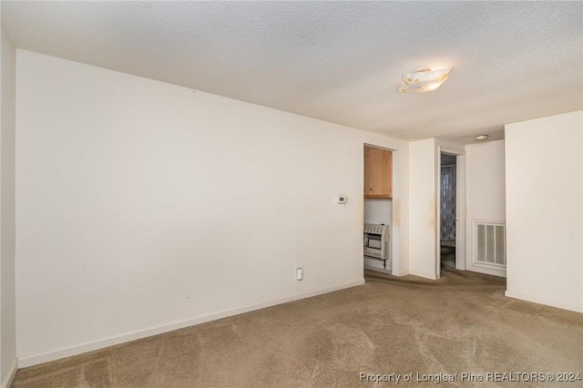 carpeted spare room with a textured ceiling and heating unit