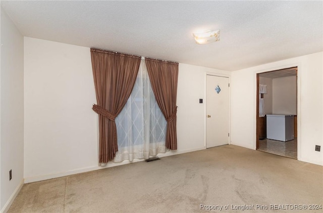 unfurnished room featuring a textured ceiling and light colored carpet