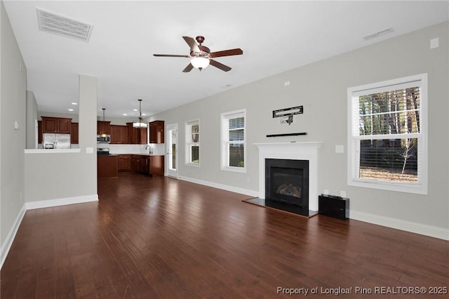 unfurnished living room with ceiling fan, dark hardwood / wood-style flooring, and sink