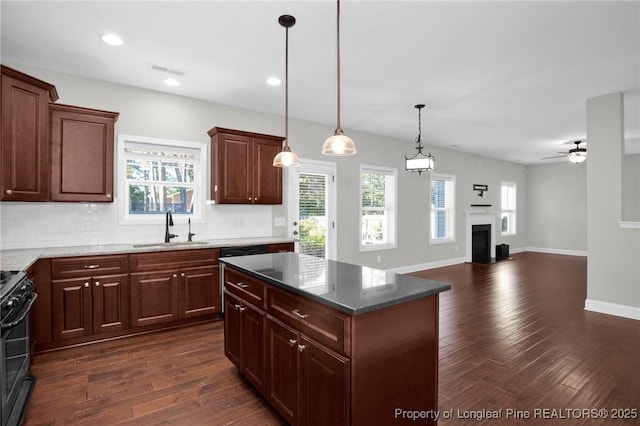 kitchen with electric range, sink, ceiling fan, hanging light fixtures, and a kitchen island