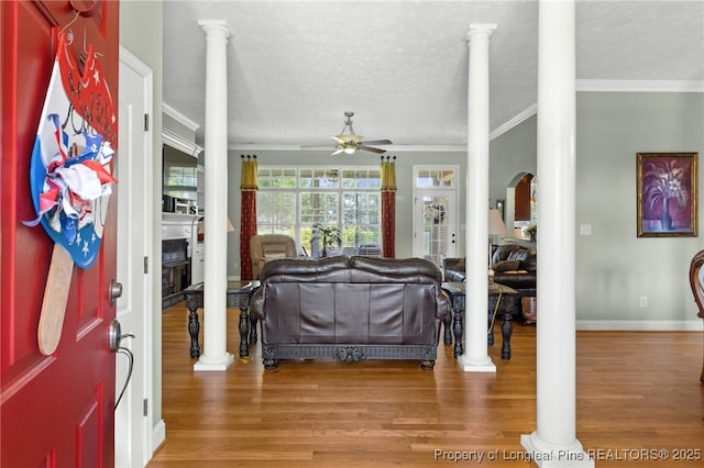 entrance foyer with crown molding, ceiling fan, wood-type flooring, a textured ceiling, and ornate columns