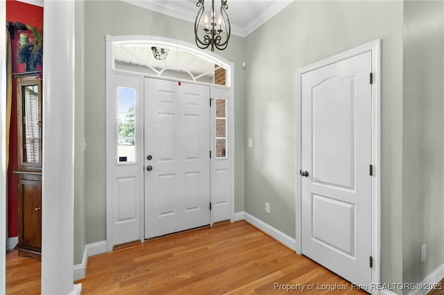 entryway with ornamental molding, a chandelier, and light hardwood / wood-style flooring