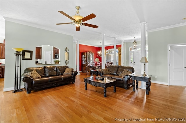 living room with crown molding, light hardwood / wood-style flooring, ceiling fan with notable chandelier, and ornate columns