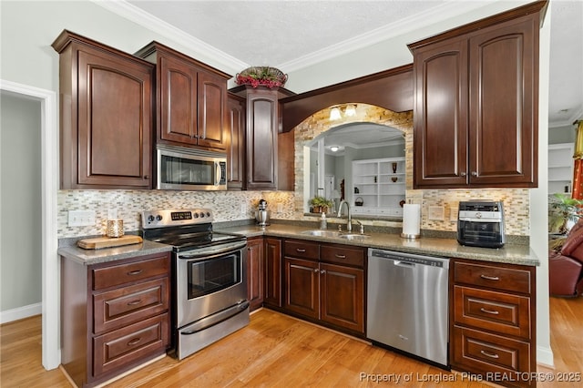 kitchen with tasteful backsplash, appliances with stainless steel finishes, sink, and light hardwood / wood-style flooring