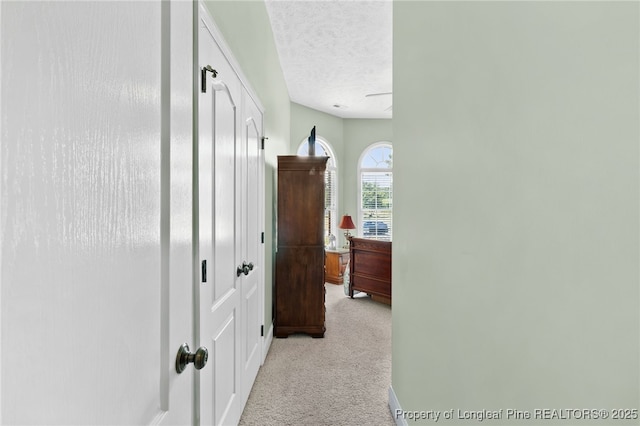 hall with light colored carpet and a textured ceiling