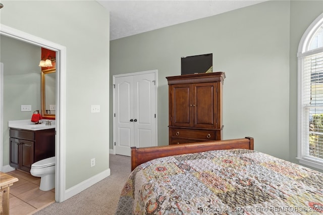 carpeted bedroom featuring sink and connected bathroom