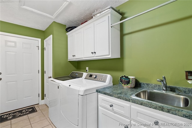 laundry area with sink, light tile patterned floors, independent washer and dryer, cabinets, and a textured ceiling