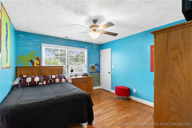 bedroom with ceiling fan, light hardwood / wood-style flooring, and a textured ceiling