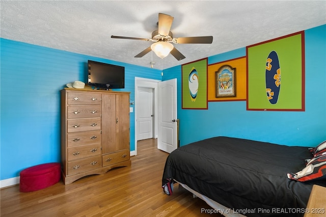 bedroom with hardwood / wood-style flooring, ceiling fan, and a textured ceiling