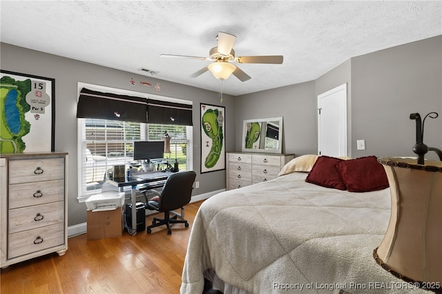 bedroom featuring ceiling fan, light hardwood / wood-style floors, and a textured ceiling