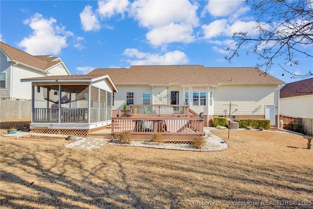 back of property with a wooden deck, a sunroom, central AC, and a lawn