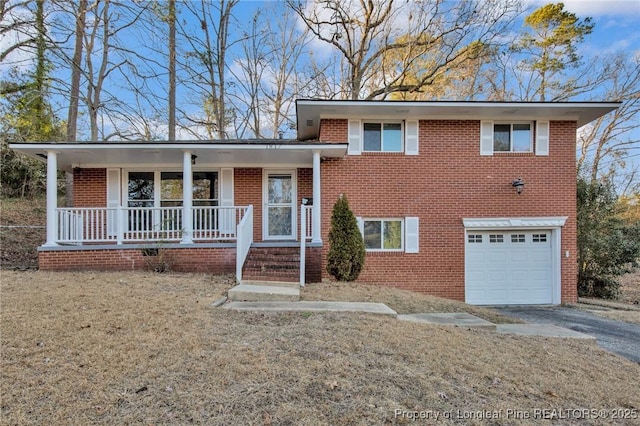 tri-level home featuring a garage, a porch, and a front yard