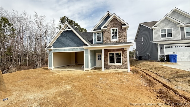 craftsman house with a garage, stone siding, and driveway