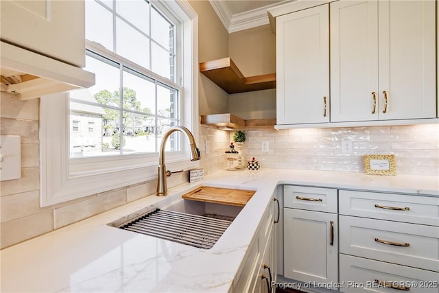 kitchen featuring tasteful backsplash, white cabinetry, ornamental molding, and sink