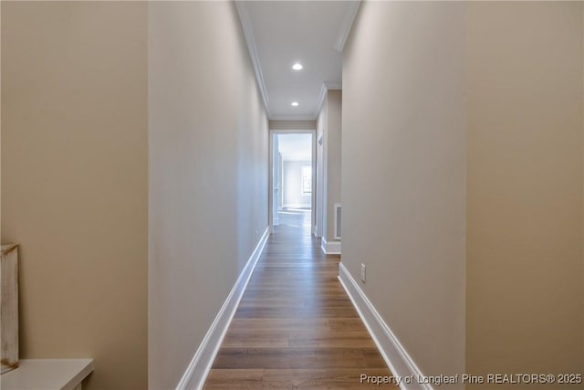 corridor with wood-type flooring and ornamental molding