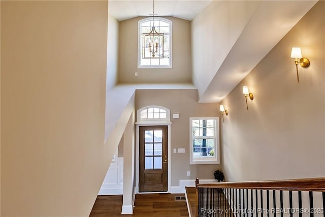 entrance foyer with dark hardwood / wood-style floors, a chandelier, and vaulted ceiling