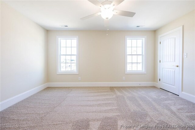 unfurnished room featuring a wealth of natural light, light colored carpet, and ceiling fan