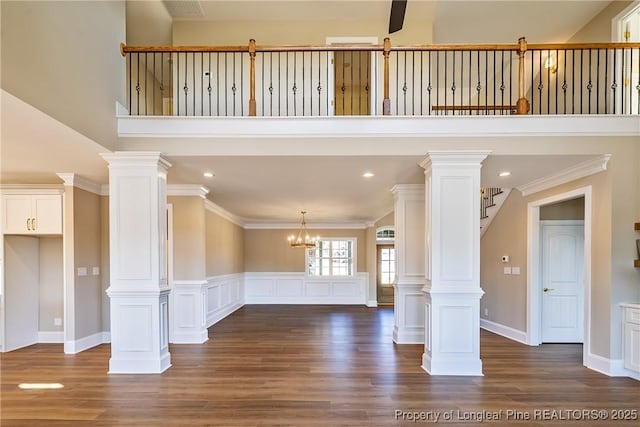 unfurnished living room featuring ornamental molding, decorative columns, and dark hardwood / wood-style floors