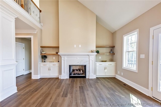 unfurnished living room featuring high vaulted ceiling, light hardwood / wood-style floors, and a premium fireplace