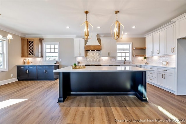 kitchen with pendant lighting, sink, crown molding, white cabinets, and blue cabinets