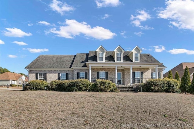 new england style home with covered porch and a front lawn