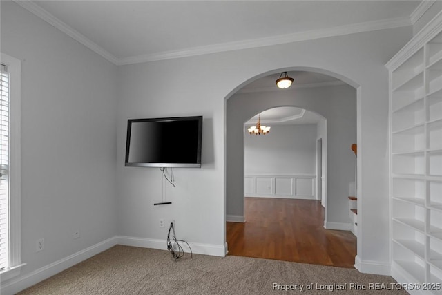 unfurnished living room featuring crown molding, built in shelves, and carpet