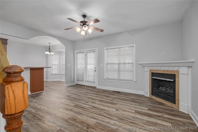 unfurnished living room with ceiling fan, dark hardwood / wood-style floors, and a tiled fireplace