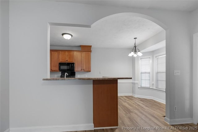 kitchen with kitchen peninsula, sink, hanging light fixtures, and light hardwood / wood-style flooring