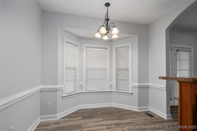 unfurnished dining area with hardwood / wood-style flooring and a notable chandelier