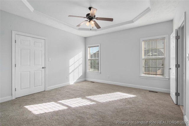 carpeted spare room with a raised ceiling, ornamental molding, and ceiling fan