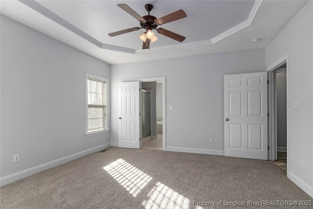 unfurnished bedroom featuring ornamental molding, a tray ceiling, and light carpet