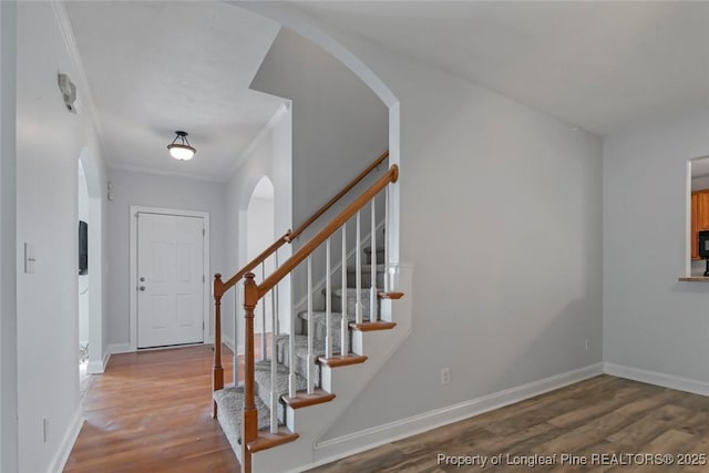 staircase featuring wood-type flooring and ornamental molding