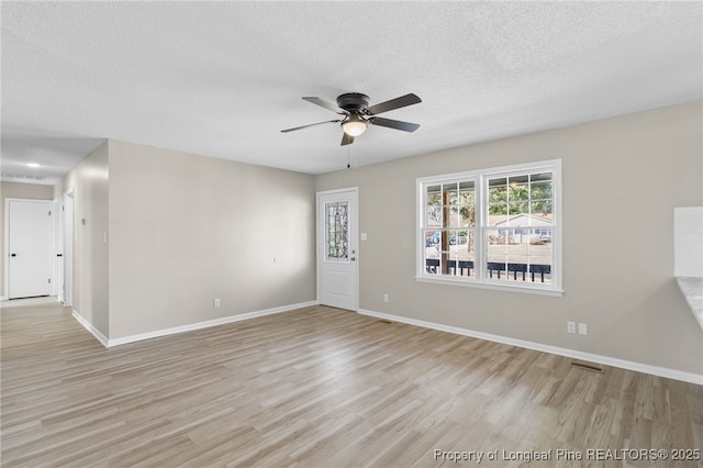 empty room with ceiling fan, a textured ceiling, and light wood-type flooring