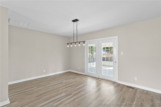 unfurnished dining area featuring light hardwood / wood-style flooring and a textured ceiling