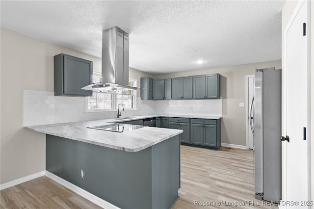 kitchen featuring gray cabinets, island range hood, stainless steel refrigerator, and kitchen peninsula