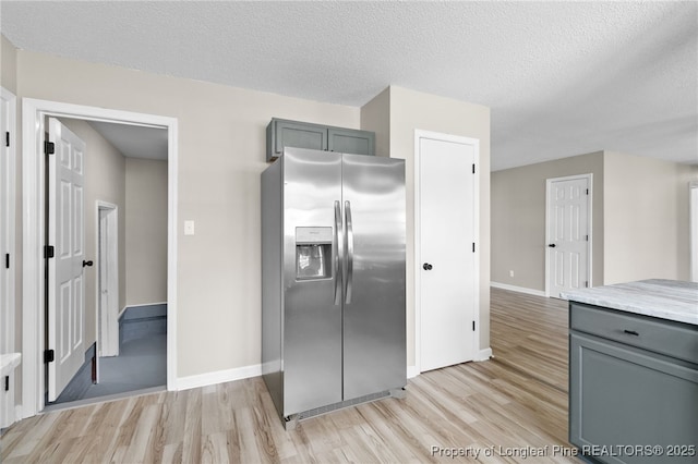 kitchen featuring light hardwood / wood-style floors, gray cabinets, stainless steel fridge with ice dispenser, and a textured ceiling